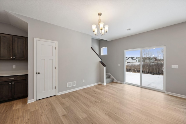 interior space featuring visible vents, baseboards, stairway, an inviting chandelier, and light wood-style floors