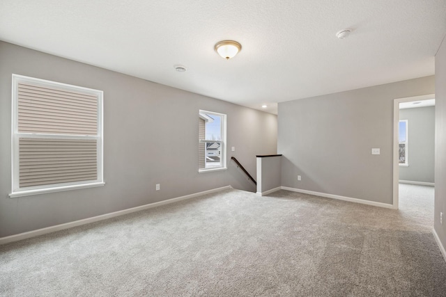 carpeted empty room featuring baseboards and a textured ceiling