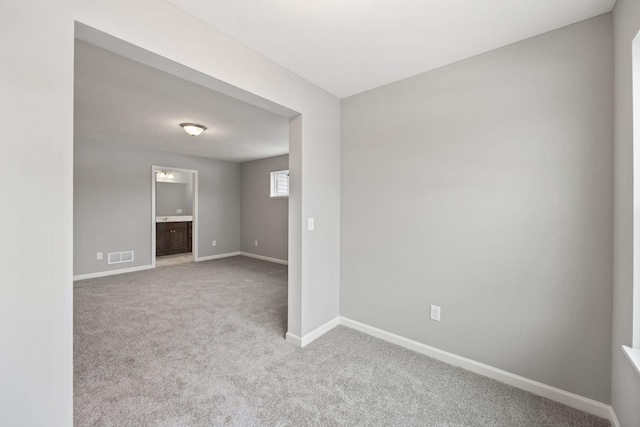 spare room with visible vents, baseboards, and carpet flooring