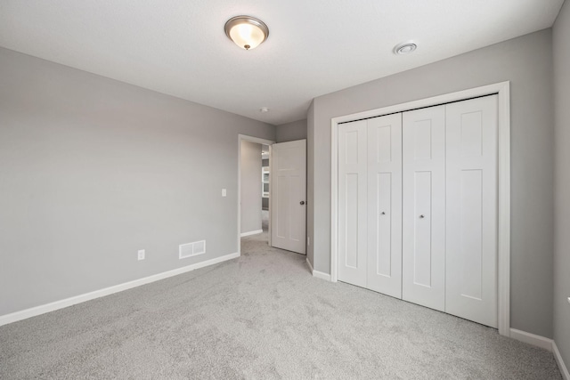 unfurnished bedroom featuring a closet, baseboards, visible vents, and carpet floors