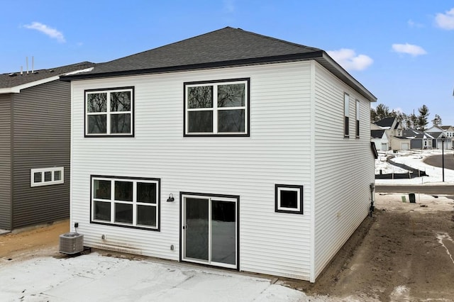 back of property with central AC unit and a shingled roof