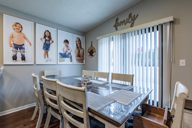 dining area featuring vaulted ceiling, wood finished floors, baseboards, and a textured ceiling