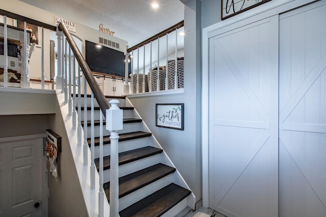 stairway with baseboards, visible vents, and a textured ceiling