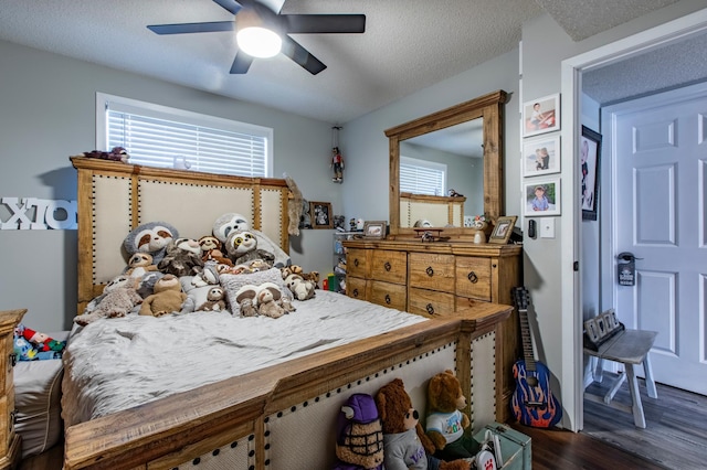 bedroom with a ceiling fan, dark wood-style floors, and a textured ceiling