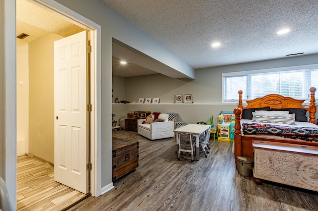 bedroom featuring visible vents, baseboards, recessed lighting, wood finished floors, and a textured ceiling