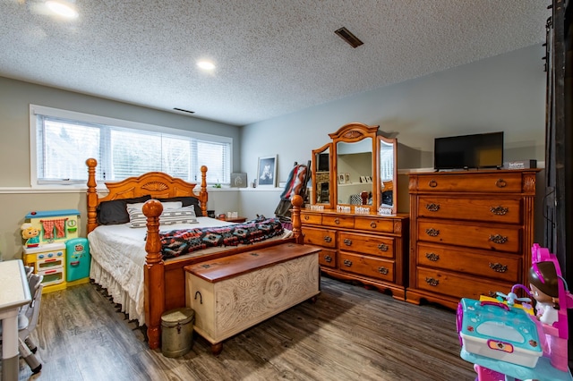 bedroom with visible vents, a textured ceiling, and wood finished floors