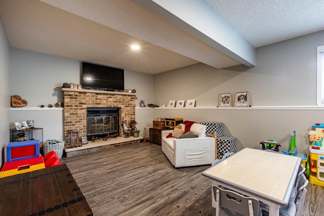 recreation room featuring a textured ceiling, wood finished floors, and a fireplace