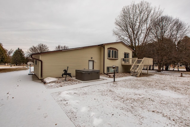 back of house featuring a wooden deck, stairs, and a hot tub