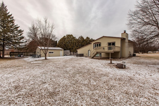 snow covered property with stairs, a deck, and a chimney