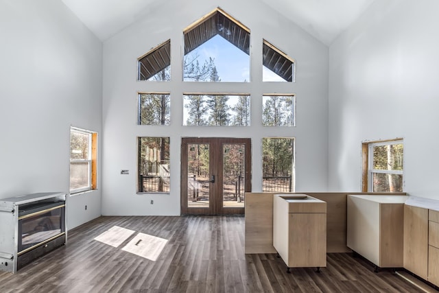 unfurnished living room featuring plenty of natural light, a high ceiling, french doors, and dark wood finished floors