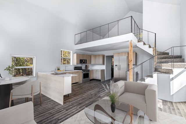 living room featuring high vaulted ceiling, wood finished floors, and stairway