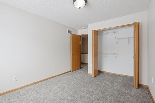 unfurnished bedroom featuring baseboards, visible vents, carpet floors, a closet, and a textured ceiling