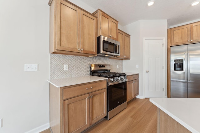 kitchen with tasteful backsplash, baseboards, light countertops, appliances with stainless steel finishes, and light wood-style floors