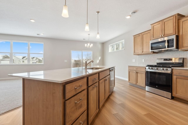 kitchen with light wood-type flooring, a sink, backsplash, appliances with stainless steel finishes, and light countertops