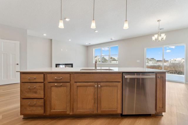 kitchen with brown cabinets, a sink, light countertops, dishwasher, and light wood-type flooring