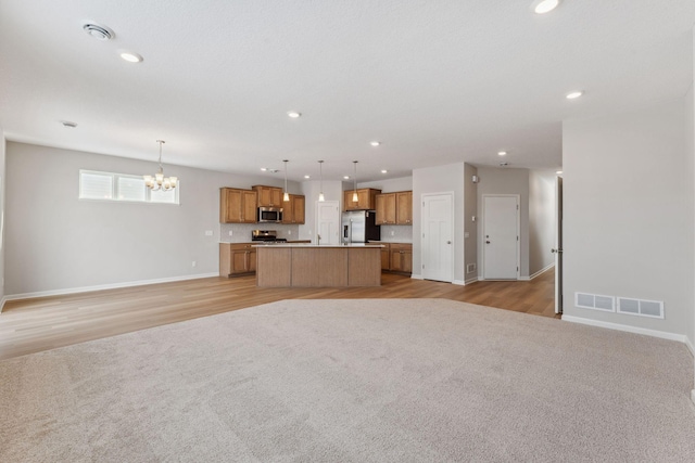 unfurnished living room featuring recessed lighting, visible vents, and a notable chandelier