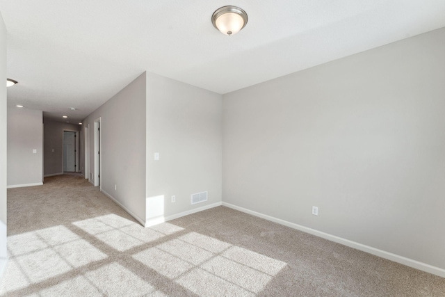 carpeted spare room featuring visible vents and baseboards