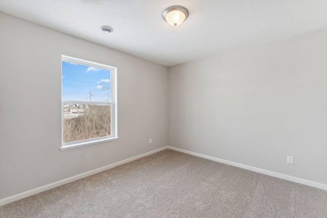 carpeted spare room featuring baseboards