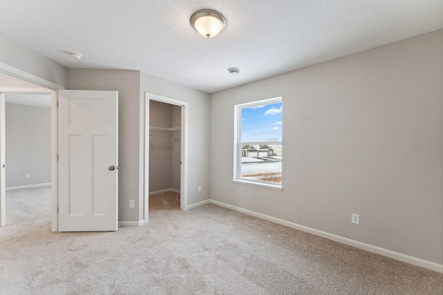 unfurnished bedroom with baseboards, a spacious closet, and carpet flooring