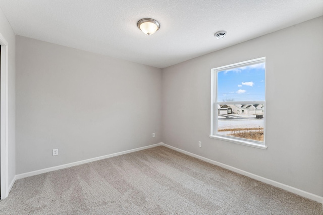 carpeted empty room with a textured ceiling and baseboards