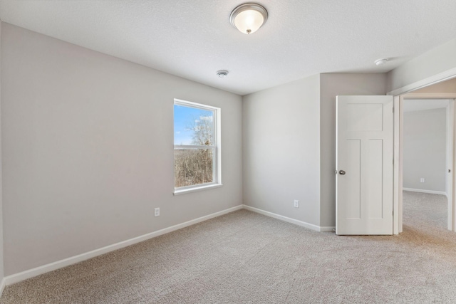 spare room featuring baseboards, a textured ceiling, and carpet flooring