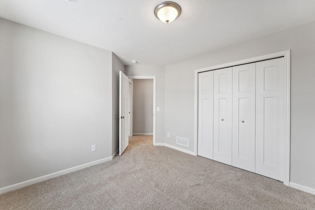 unfurnished bedroom with visible vents, baseboards, carpet floors, a closet, and a textured ceiling