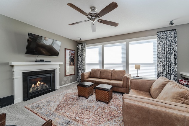 living room featuring baseboards, carpet floors, ceiling fan, and a fireplace with flush hearth