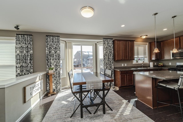 kitchen with a sink, recessed lighting, appliances with stainless steel finishes, baseboards, and dark wood-style flooring