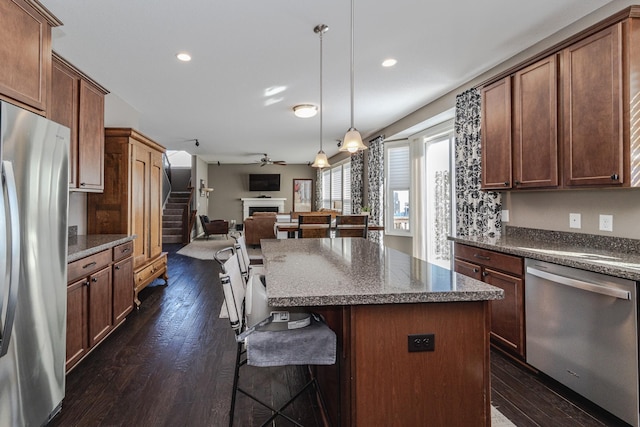 kitchen with stainless steel appliances, a kitchen bar, dark wood finished floors, and a fireplace