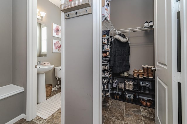 walk in closet featuring stone finish flooring