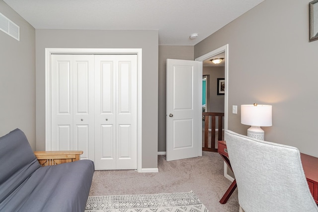 interior space with a closet, visible vents, light colored carpet, and baseboards