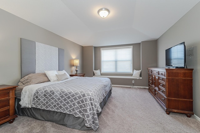 bedroom with baseboards, light carpet, and a raised ceiling