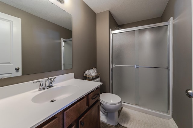 bathroom with toilet, a stall shower, vanity, and a textured ceiling