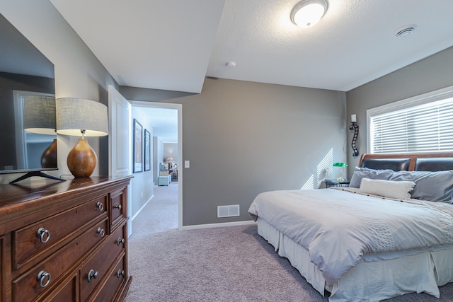 carpeted bedroom with visible vents, a textured ceiling, and baseboards