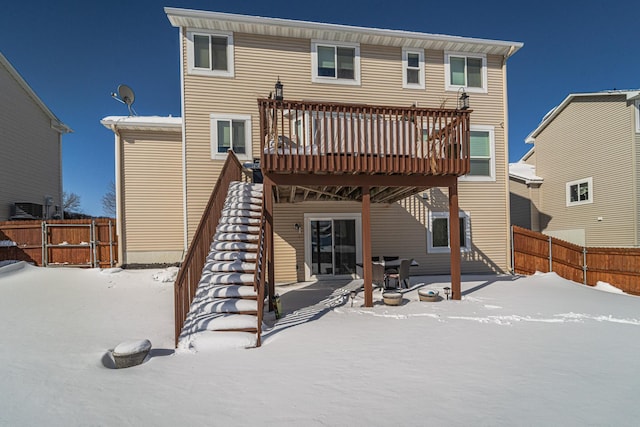 snow covered rear of property featuring a patio area, stairway, fence, and a wooden deck