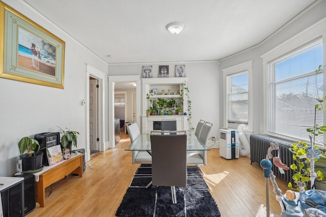 dining space with radiator, light wood-style flooring, and crown molding