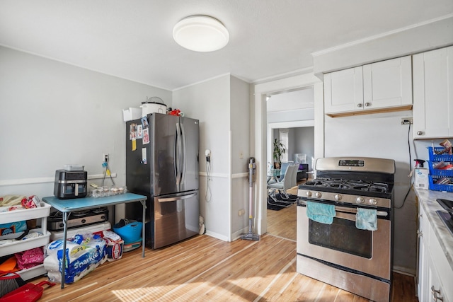 kitchen with baseboards, ornamental molding, white cabinets, appliances with stainless steel finishes, and light wood-type flooring