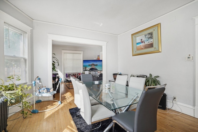 dining area featuring baseboards, hardwood / wood-style floors, and crown molding