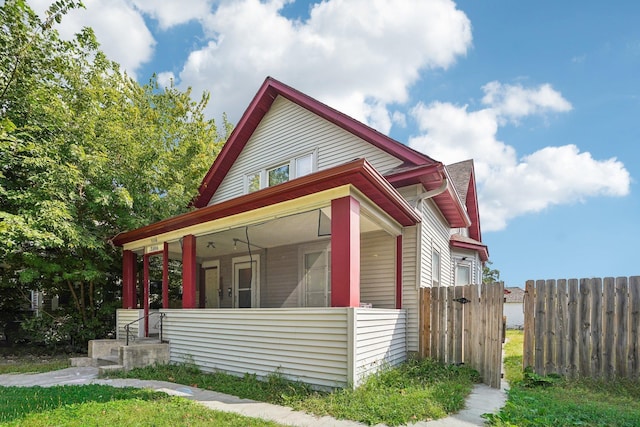 view of side of home featuring covered porch and fence