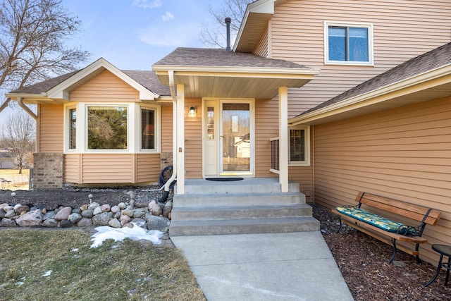 view of exterior entry with a shingled roof