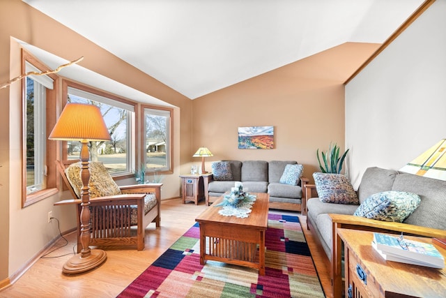 living area with lofted ceiling, baseboards, and light wood finished floors