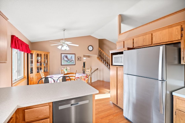 kitchen featuring lofted ceiling, ceiling fan, light countertops, appliances with stainless steel finishes, and light wood-type flooring