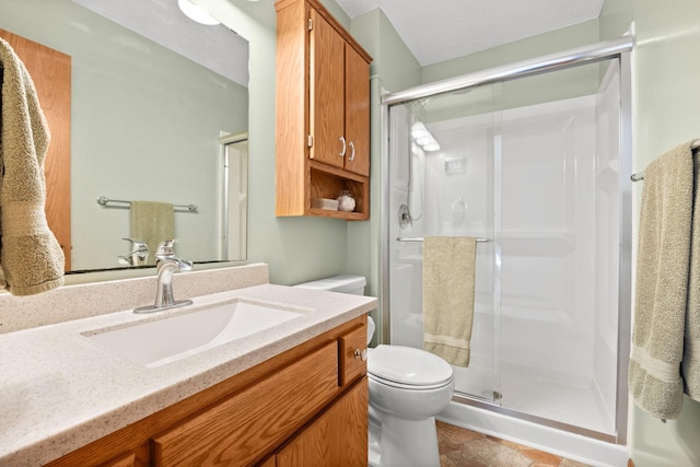 bathroom featuring vanity, a shower stall, and toilet