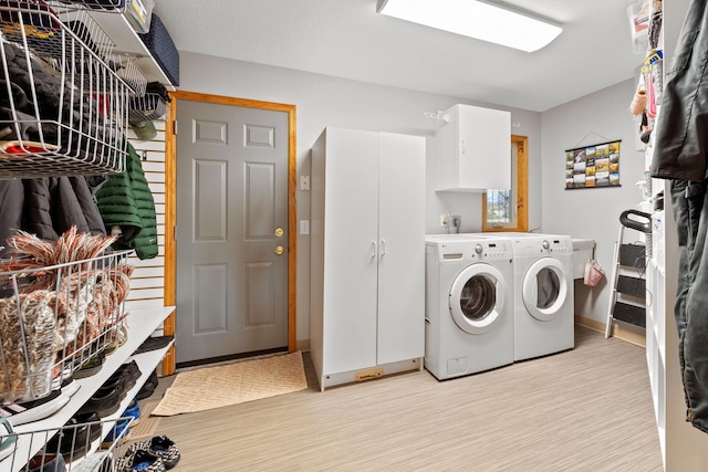 clothes washing area featuring light wood-type flooring, baseboards, and washing machine and clothes dryer