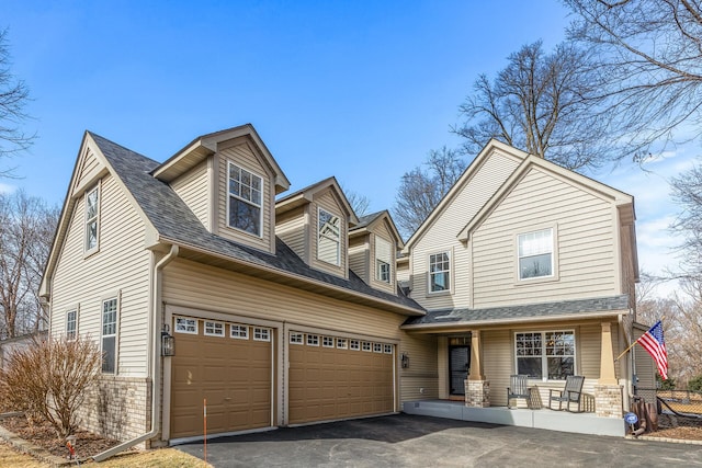 view of front of house featuring aphalt driveway, roof with shingles, a porch, and an attached garage