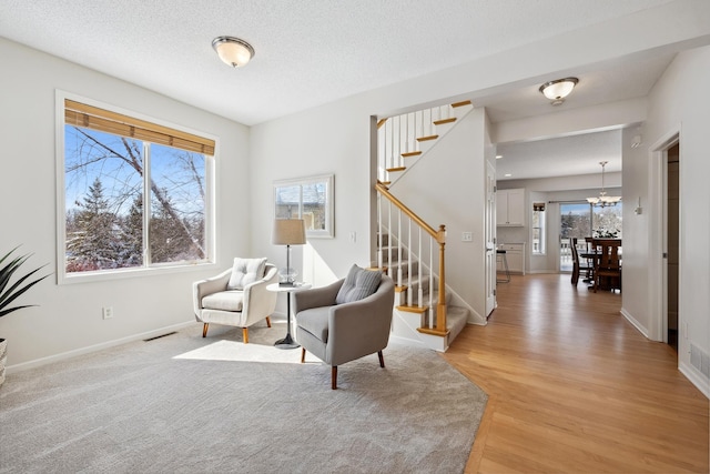 sitting room featuring visible vents, baseboards, stairway, a notable chandelier, and a textured ceiling