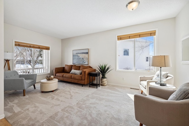 living room featuring baseboards, light colored carpet, and a textured ceiling