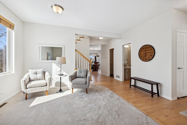 living area with a notable chandelier, stairway, baseboards, and wood finished floors