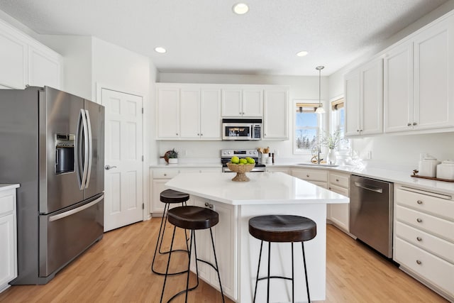 kitchen featuring a sink, stainless steel appliances, a kitchen breakfast bar, and light wood-type flooring