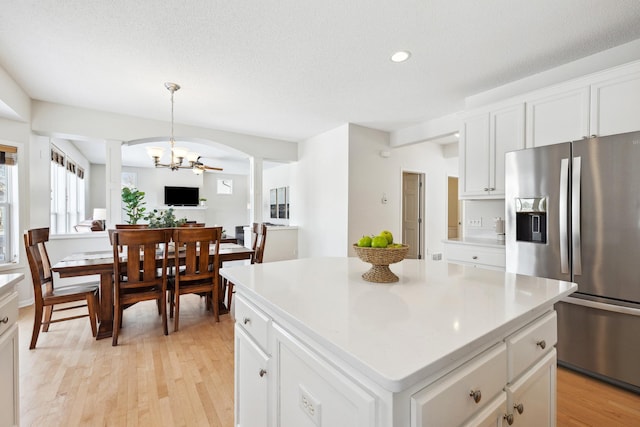 kitchen featuring light wood finished floors, stainless steel refrigerator with ice dispenser, a kitchen island, white cabinets, and light countertops